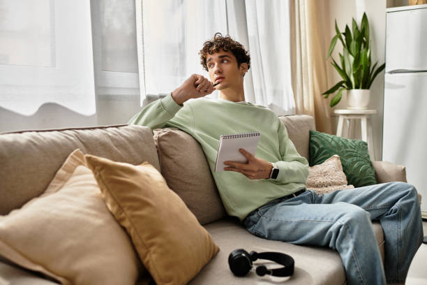 istock Young man with curly hair thinks creatively while working from home in a cozy room 2180962943