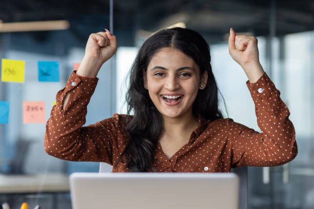 istock Excited young woman celebrating success at work in modern office with colorful sticky notes 2180963110