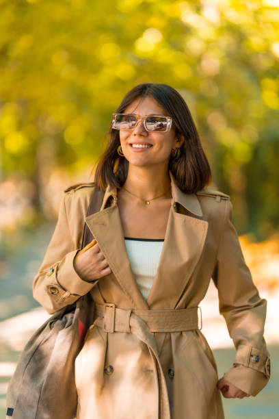 istock A woman wearing a brown coat and sunglasses is walking down a path 2180966643