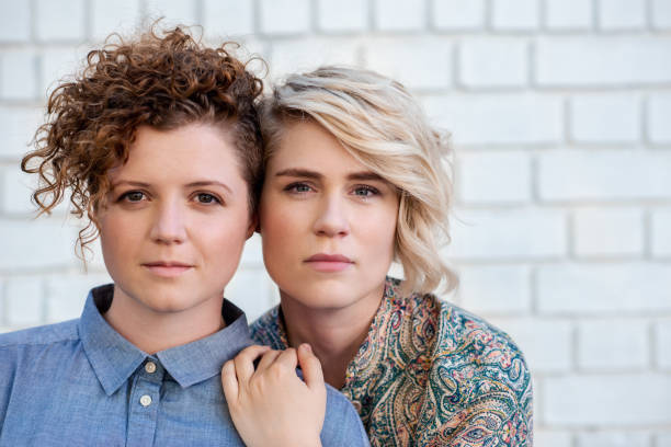 Portrait of a young lesbian couple standing together in front of a brick wall outside