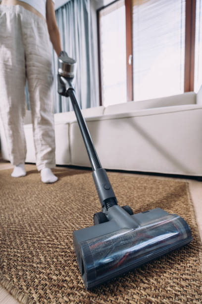 istock Woman cleaning floor using vacuum cleaner on carpet 2180973791