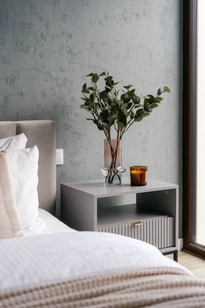 istock Bedside table with candle and home decor next to neatly made bed 2180975072