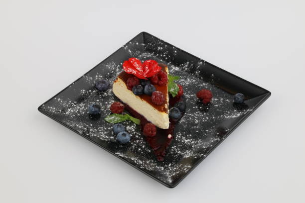 istock Tasty cheesecake with berries and sauce on a black plate on a white background 2180975485