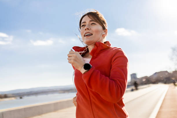 istock Smiling Sportswoman Jogging Along a Scenic River Path 2180975639
