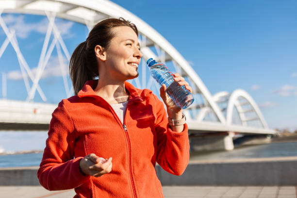 istock Carefree Runner Pauses to Hydrate by the River on a Beautiful Morning 2180975724