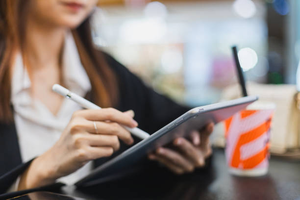 istock Beautiful young asian woman using tablet sitting at cafe. Working lady relax positive expression cheerful. Female black suit working outside. 2180978537