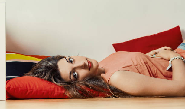 A cheerful woman enjoys her time on a cozy bed, surrounded by soft pillows and a serene atmosphere.