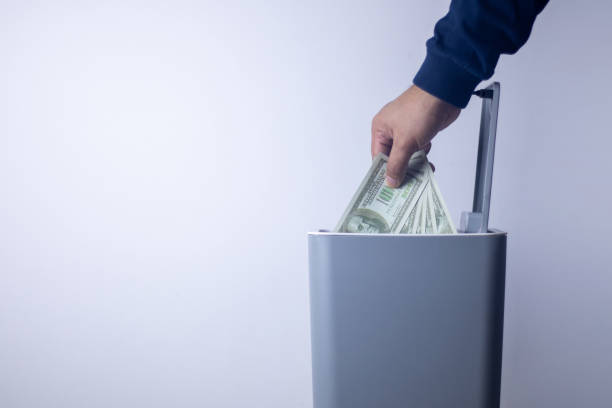 istock A man's hand tossing money into a trash bin. 2180981466