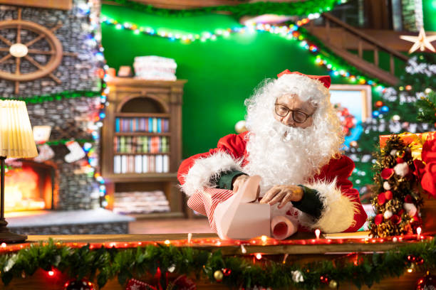 istock Father Christmas prepares a beautifully wrapped gift box in his workshop 2180983052
