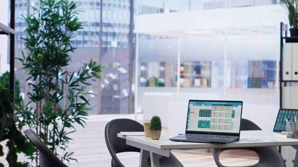 istock Laptop on desk next to files with forex trading analytics, cityscape backdrop 2180990790