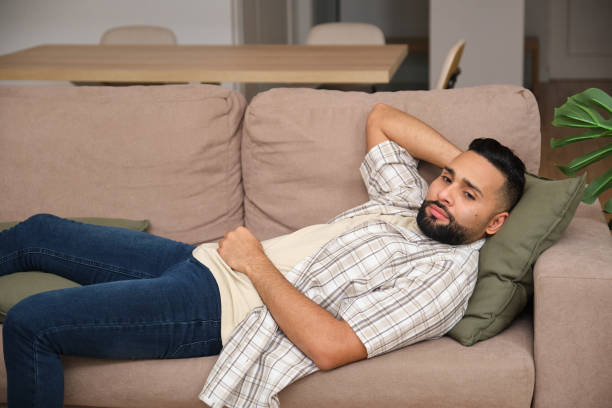 istock Young man relaxing on sofa at home looking at camera 2180995323