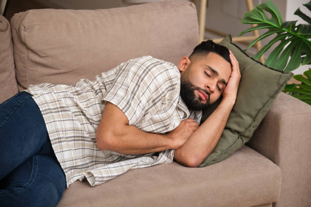 istock Young man sleeping peacefully on sofa at home 2180995508