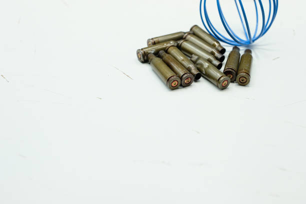 Earth in Danger Concept. Minimalist Migration Concept with Bullet Casings and Symbol Earth during the War. Conflict and Reflection. Scratched White Surface. Copy Space.