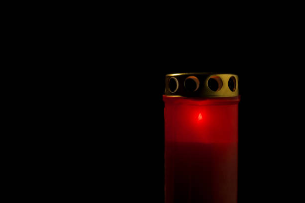 Red cemetery candle, on a black background, close up shot. All saints day concept.