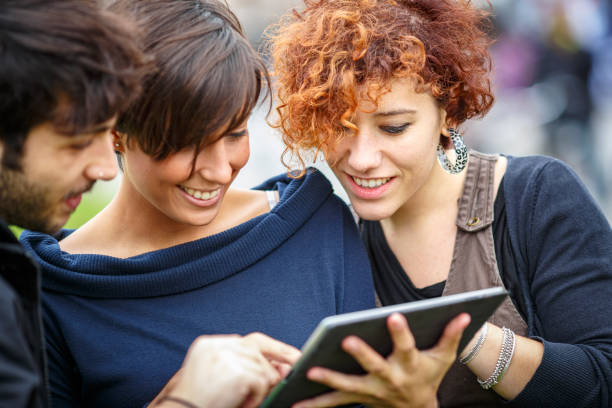 istock Students using tablet and smiling in front of pisa cathedral, italy 2180997157