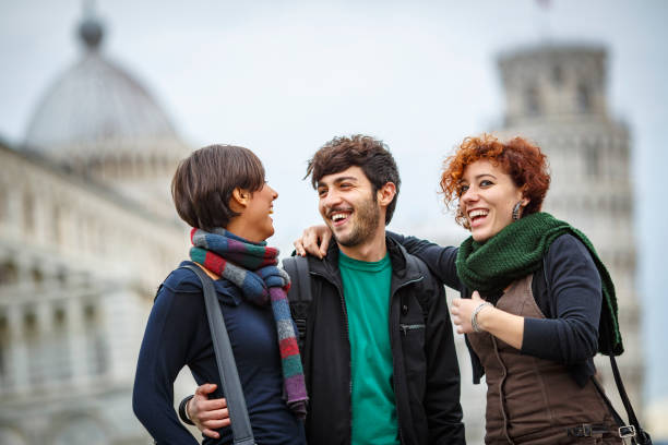 Happy tourists laughing together in front of the leaning tower of pisa stock photo