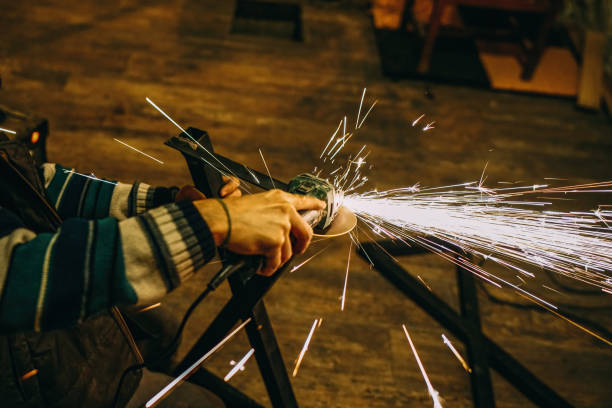 istock Professional blacksmith creates large colorful sparks as he cuts an iron bar with a cutter. 2180999461