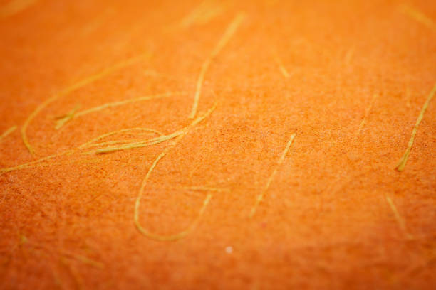 Extreme closeup of orange handmade paper with shallow depth of field.