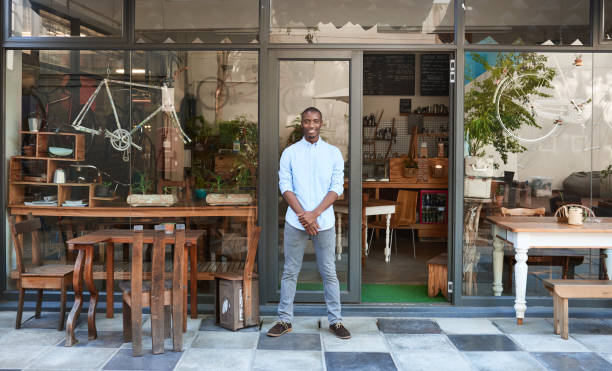 istock Smiling African entrepreneur standing welcomingly in front of his cafe 2181004261