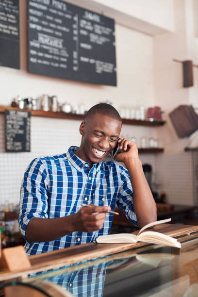 istock Smiling young African entrepreneur hard at work in his cafe 2181005199