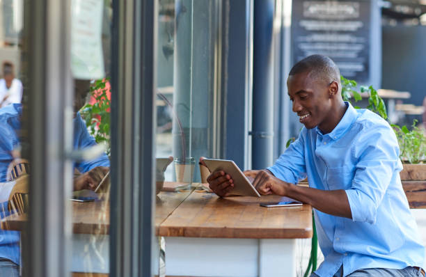 istock Young African man working online at a sidewalk cafe table 2181005394