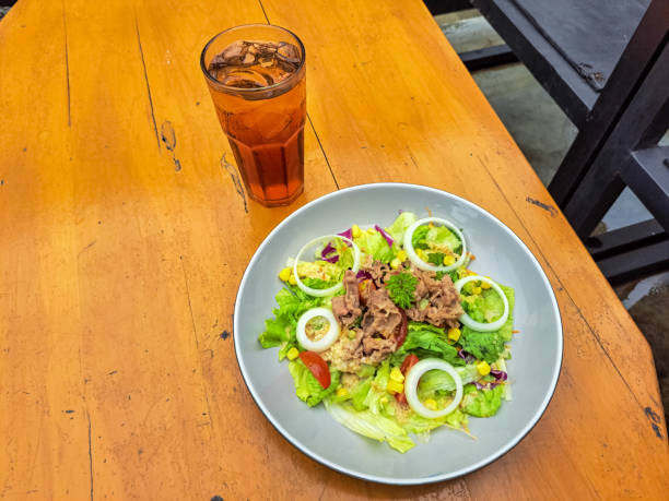 Tokyo Beef Salad With Sesame Dressing - Grilled Beef Slices Served with Lettuce, Purple Cabbage With Sesame Sauce, Roasted, Corn, Cherry Tomatoes And Sliced ​​Onions. Fresh Tea Iced In Glass. Food And Drink Menu.