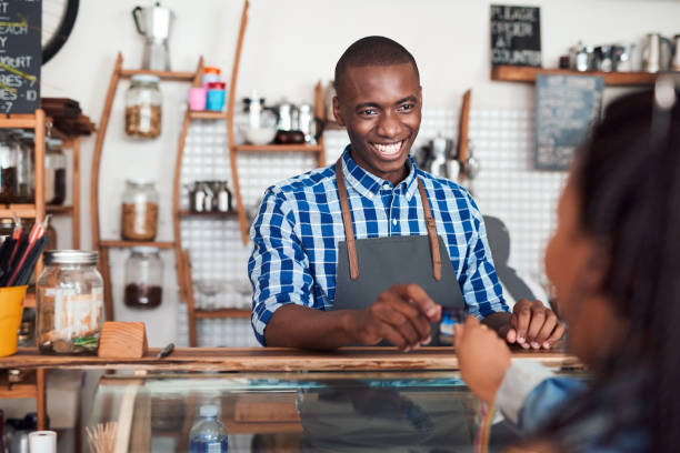istock Smiling barista taking a credit card from a cafe customer 2181006512
