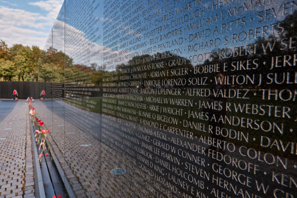 Washington DC, USA - October, 3, 2016: The Vietnam Veterans Memorial in Washington D.C. features names etched in granite. Flowers honor the fallen soldiers in tranquil surroundings.