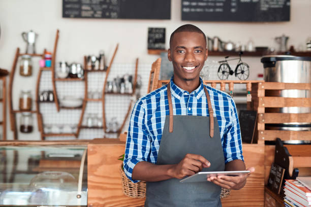 istock Smiling entrepreneur standing in his cafe using a digital tablet 2181007233