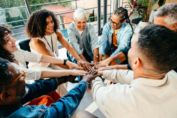 istock Diverse group of people coming together, placing hands in unity during a team building session in a modern office setting. 2181008273