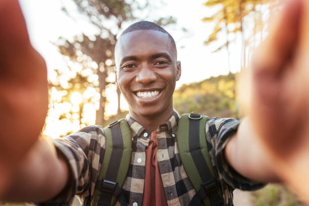 istock Smiling young African man taking selfies while hiking alone outdoors 2181009352