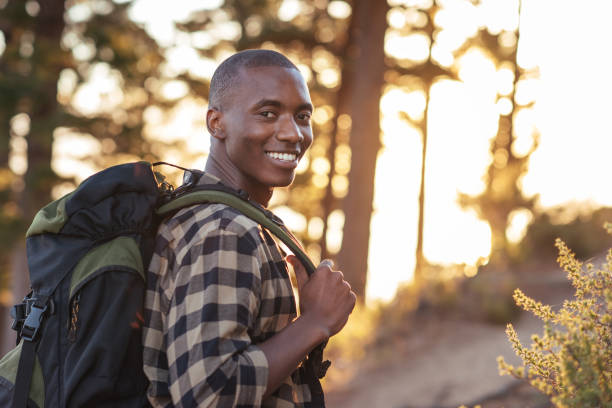 istock Smiling young African man hiking along a trail at dusk 2181010086