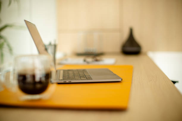 An office desk setup with a coffee mug beside a laptop, placed on a wooden surface, embodying productivity and focus, with a minimalist approach.