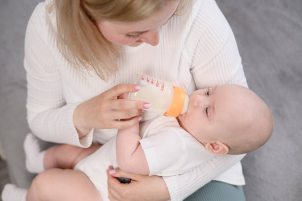 istock Woman lovingly and patiently feeds infant from a bottle with formula, making sure that child feels safe and comfortable at time. Concept of feeding newborns, an alternative to breastfeeding. 2181013842