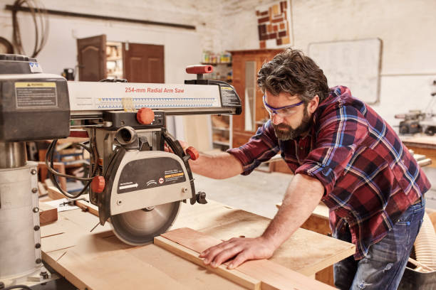 istock Carpenter using radial arm saw to cut wood in workshop 2181014318