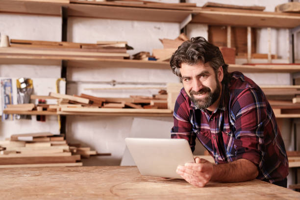istock Smiling small business owner in woodwork studio with digital tab 2181016107
