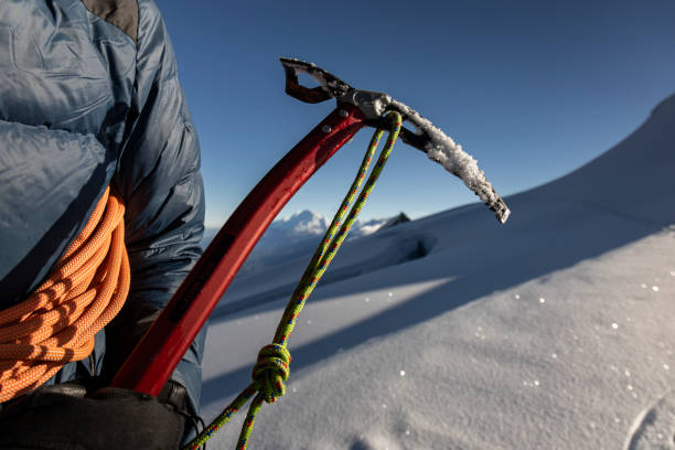 Man's hands holding a snow axe, safety equipment for snow climbing