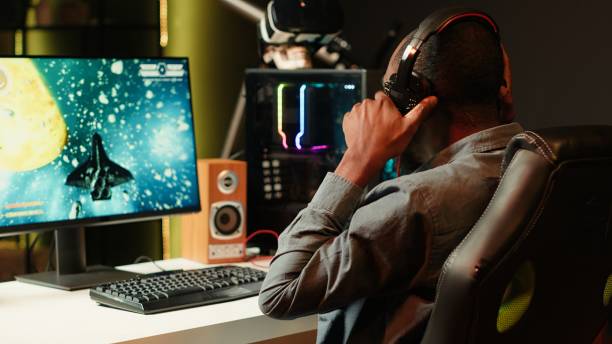 istock Man playing SF shooter videogame, talking into headset with friends 2181034354