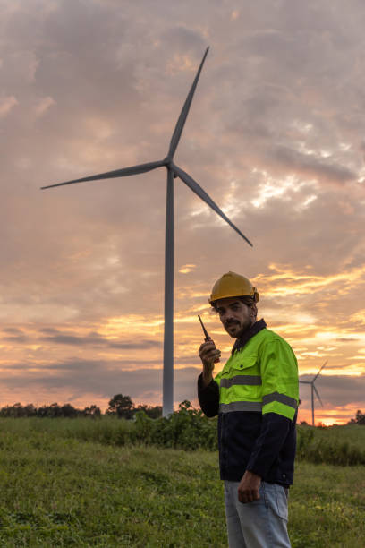 istock Professional Man Maintenance engineers working in wind turbine farm at sunset. Engineer Man standing among Wind Energy Turbine. 2181034396