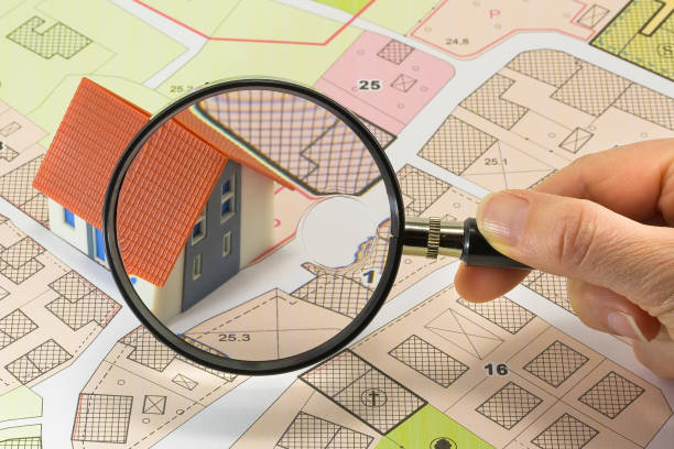 istock Searching new home - Concept with home model, magnifying glass and imaginary cadastral map 2181035069