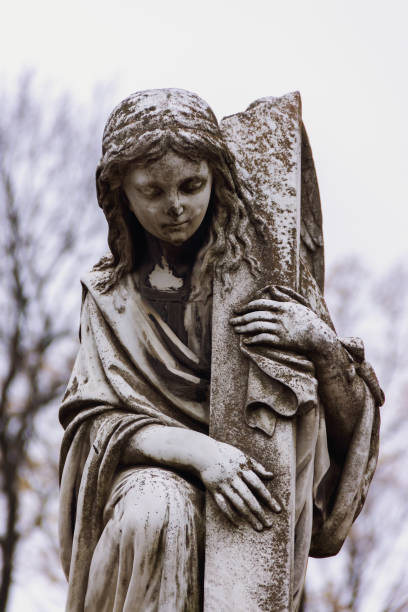 A weathered angel looking as though he's walking back to heaven carrying his bundle of flowers he had just picked.