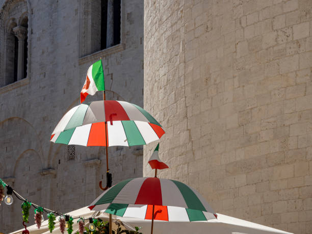 Umbrellas in the national colors of Italy against the background of the walls of medieval buildings.