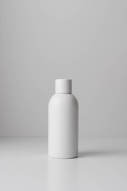 istock White bottle on a light background with shadows of plant leaves 2181048254