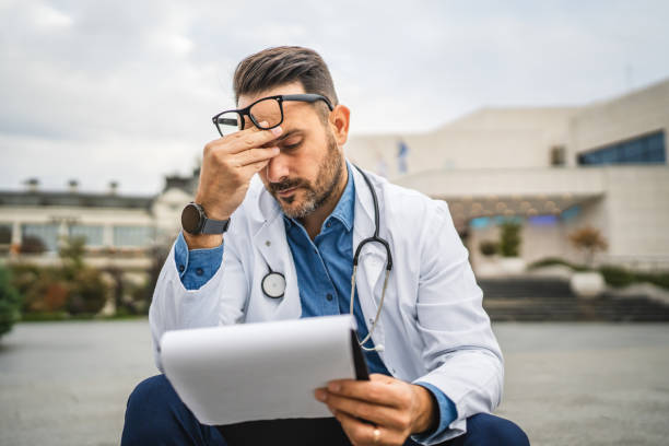 istock exhausted worried doctor read information from clipboard 2181062872