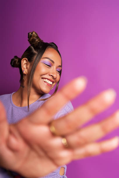 istock Young woman laughing and extending hand on purple background 2181063254
