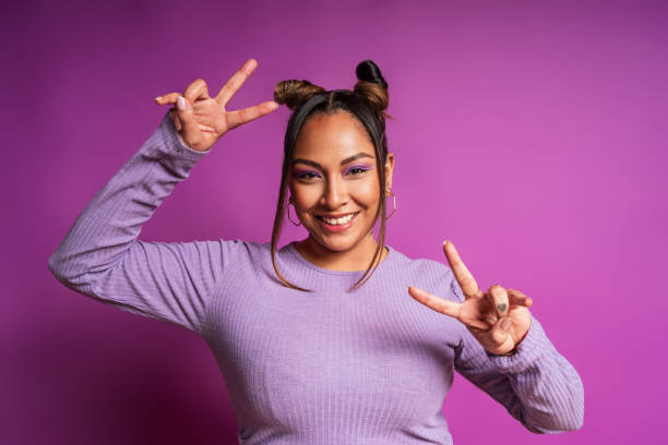 istock Young influencer making peace sign with both hands and smiling on purple background 2181063270