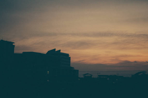 Silhouette of a building and radio tower against a golden sunset sky in Bangkok, Thailand