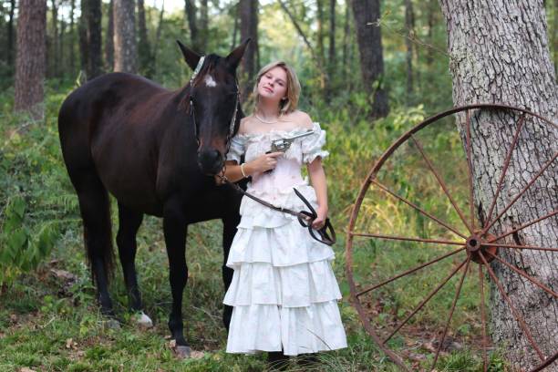 Group of cowboy and cowgirl stay near fence in grasses field and they also bring horse beside of them.