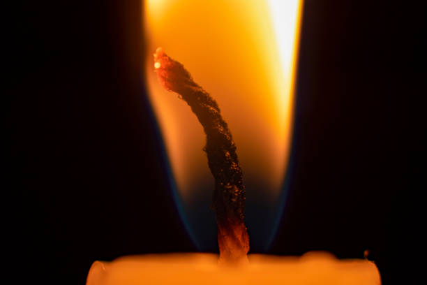 Front view of red color candle with flame with white color background.
