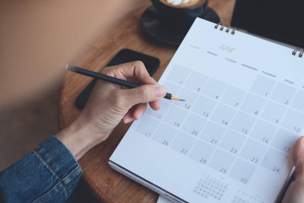 istock 2025 Event planner timetable agenda plan on schedule event. Business woman checking planner, taking note on calendar desk on office table. Calendar event plan, work planning 2181089245